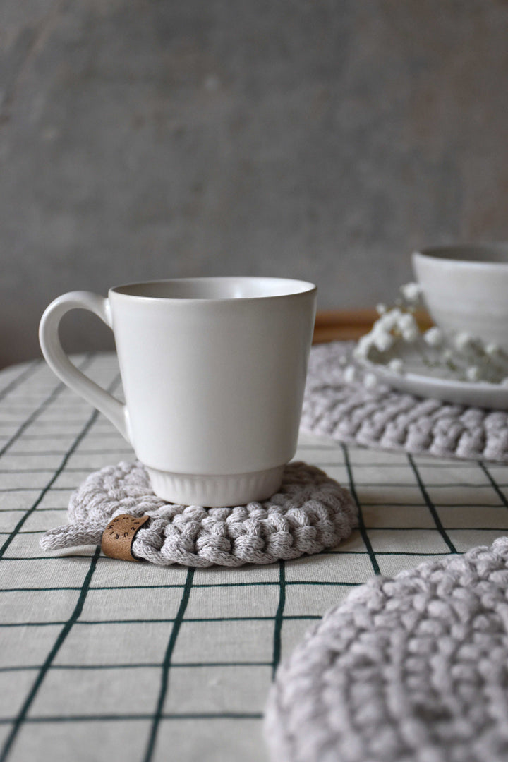 White mug on a textured gray coaster with a blurred background