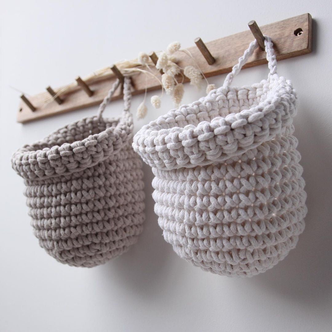 Crochet hanging bags in white and beige colour on the wooden peg hanger