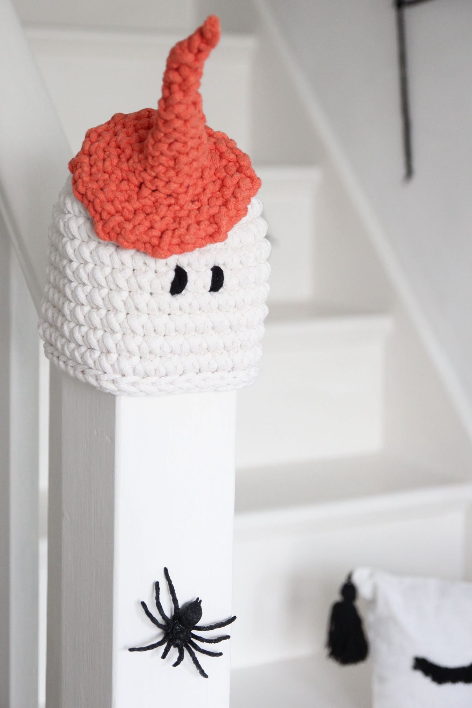 White and red knitted ghost decoration on a staircase with spider decorations.