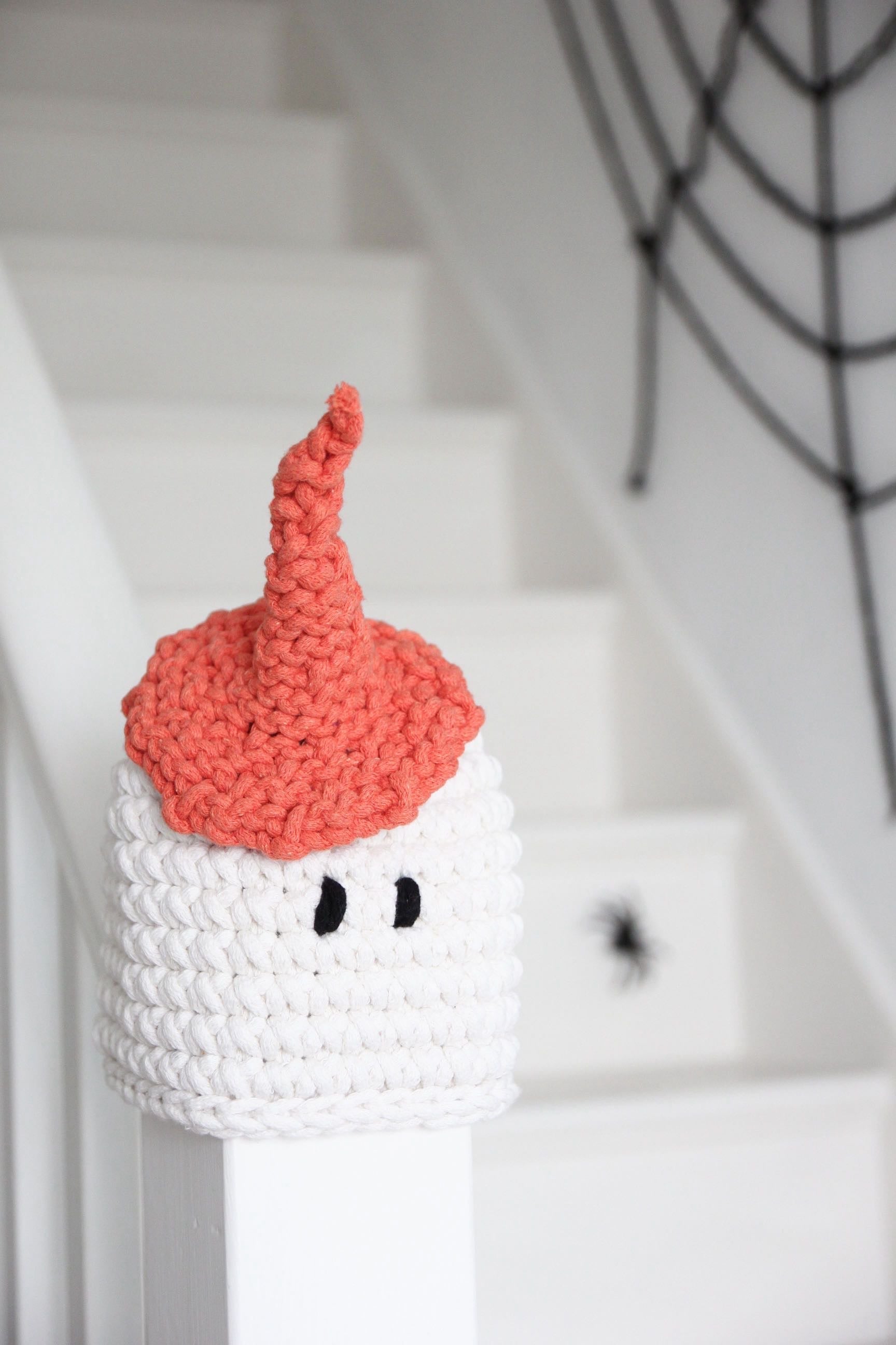 Crocheted ghost with a red hat on a staircase