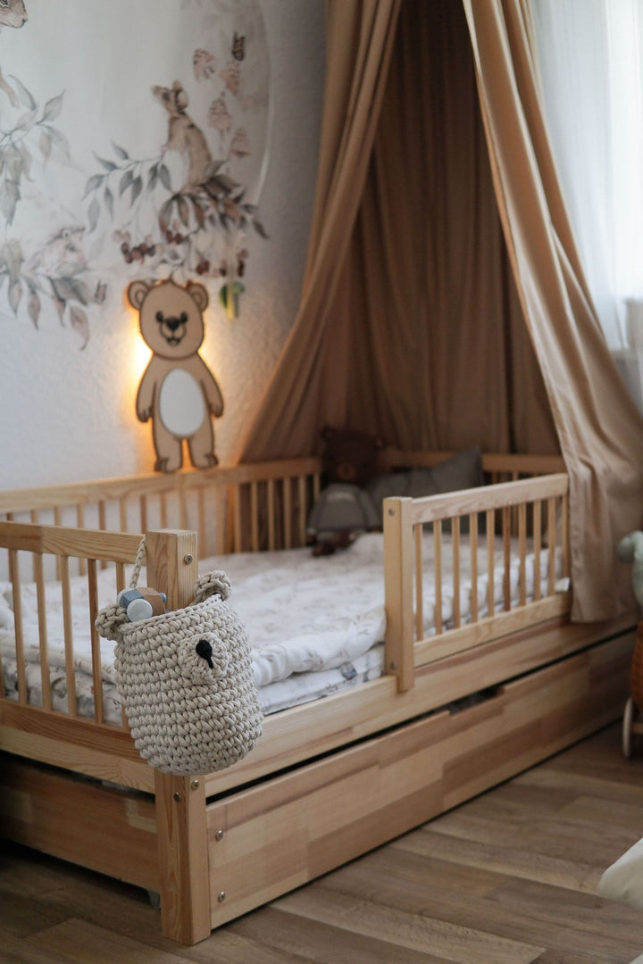 boys bedroom with wooden bed and a crochet hanging bear basket