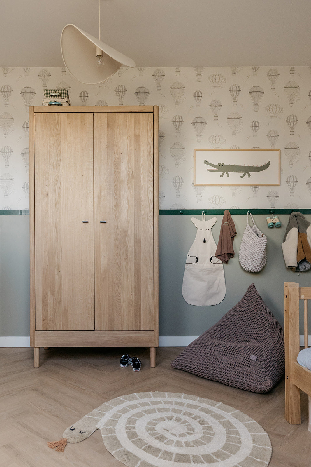 Children's room with wooden wardrobe, bean bag, and wall art.