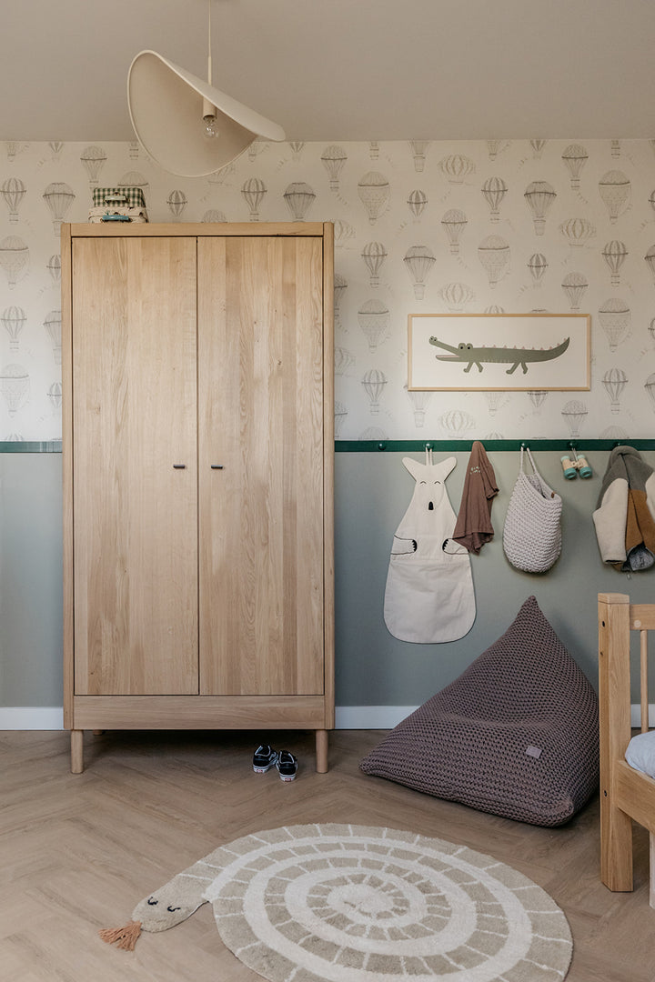 Children's room with wooden wardrobe, bean bag, and wall art.
