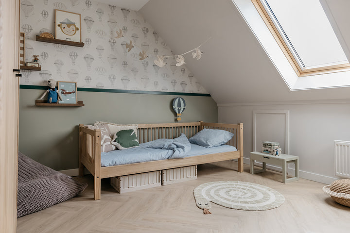 Children's bedroom with wooden bed, decorative pillows, and wall art.