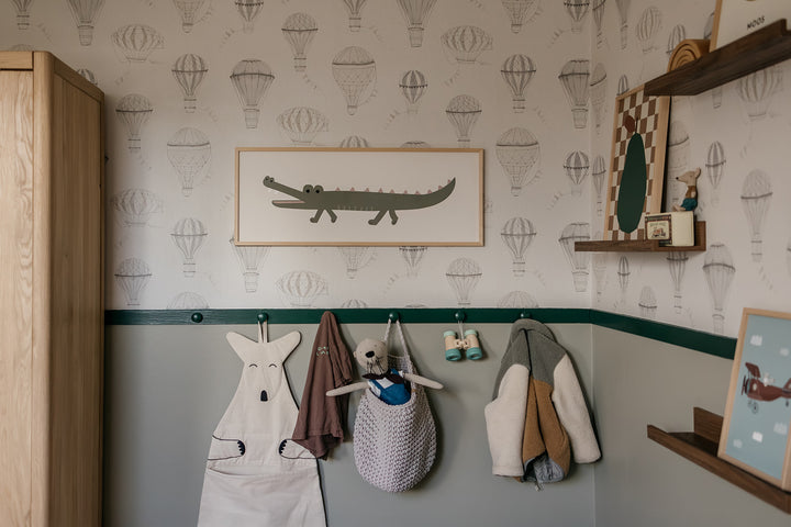 Children's room with wall hooks displaying various items against a wallpapered wall.