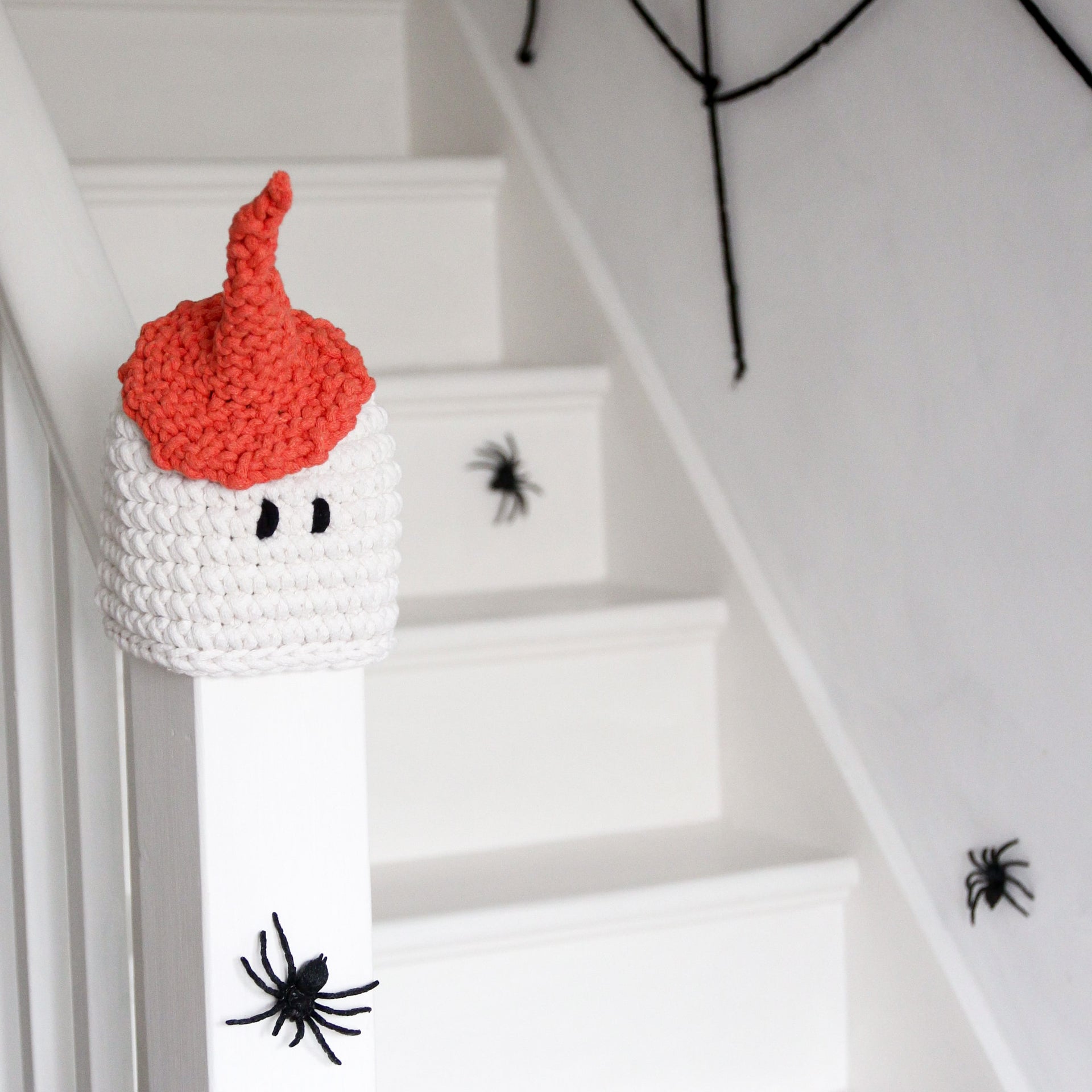 Crocheted ghost with red hair on a staircase with spider decorations
