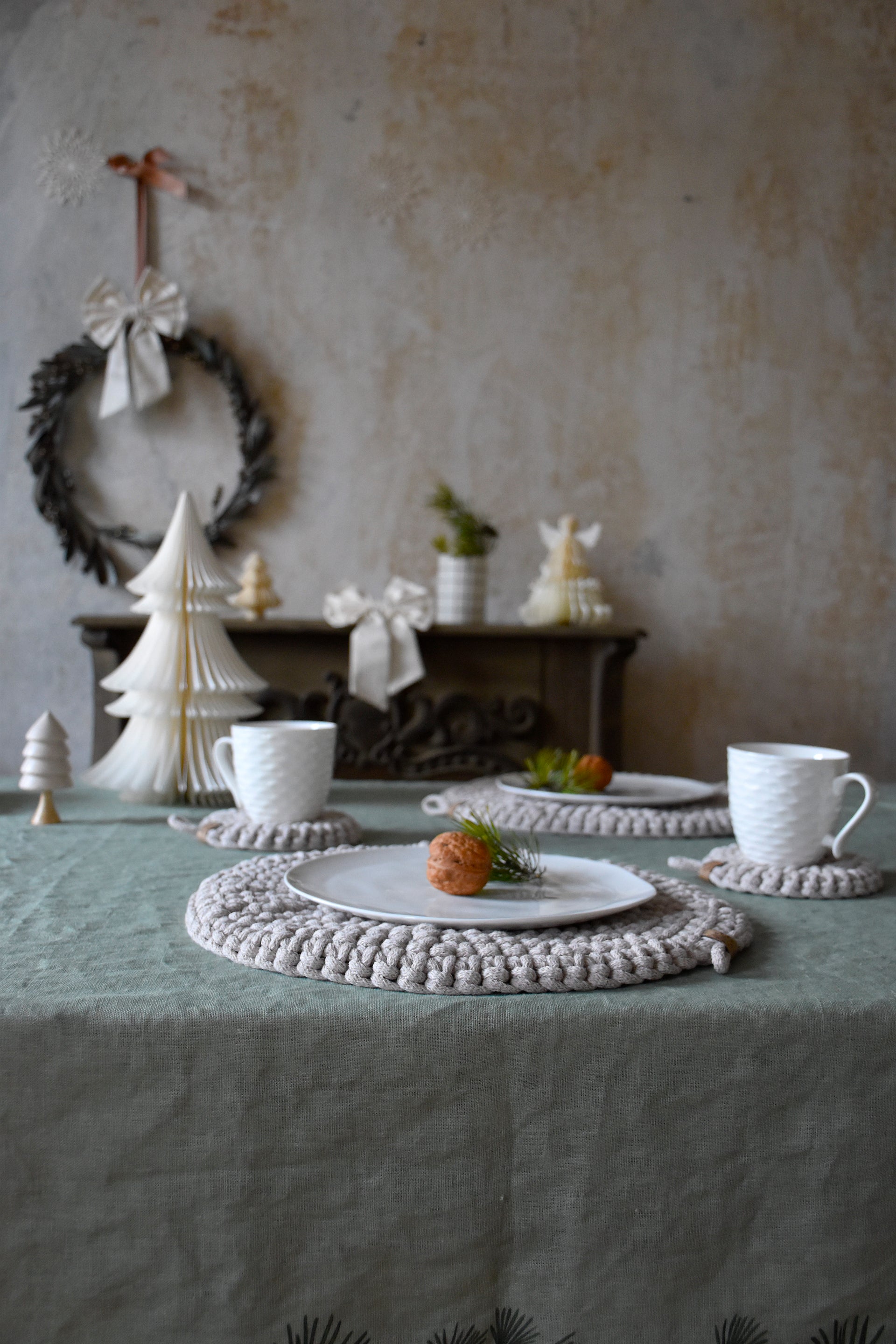 Set table with crocheted placemats and decorative items against a textured wall.