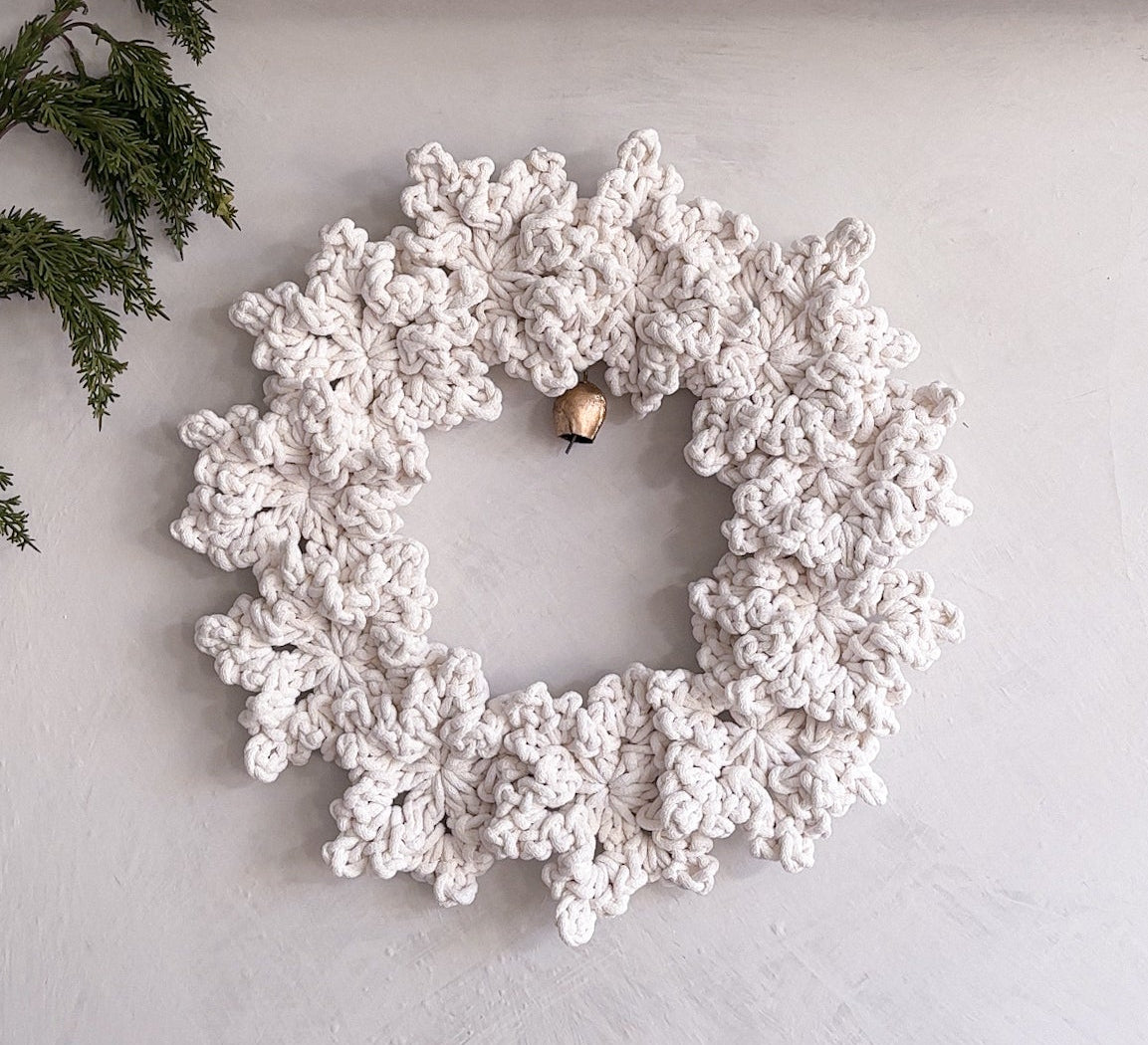 White wreath on a white wall with decorative houses and greenery.