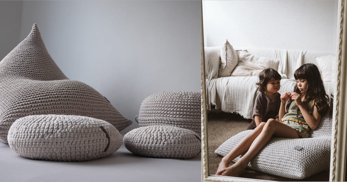 Knitted bean bags on a plain background with two children sitting on a bean bag in a bedroom.