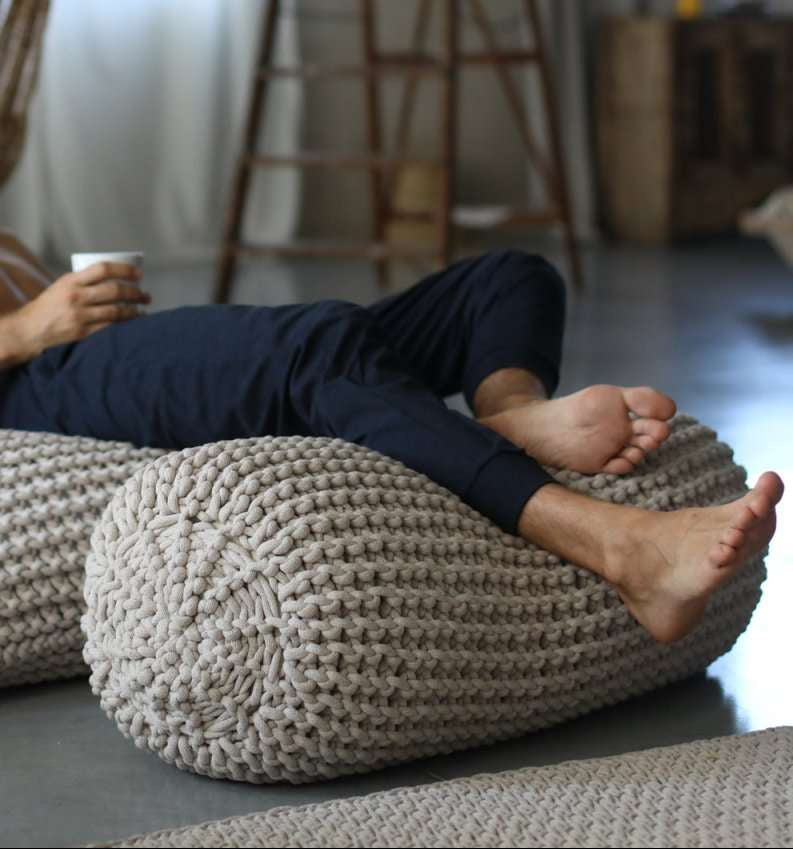 Chunky knitted footrest with human feet placed on