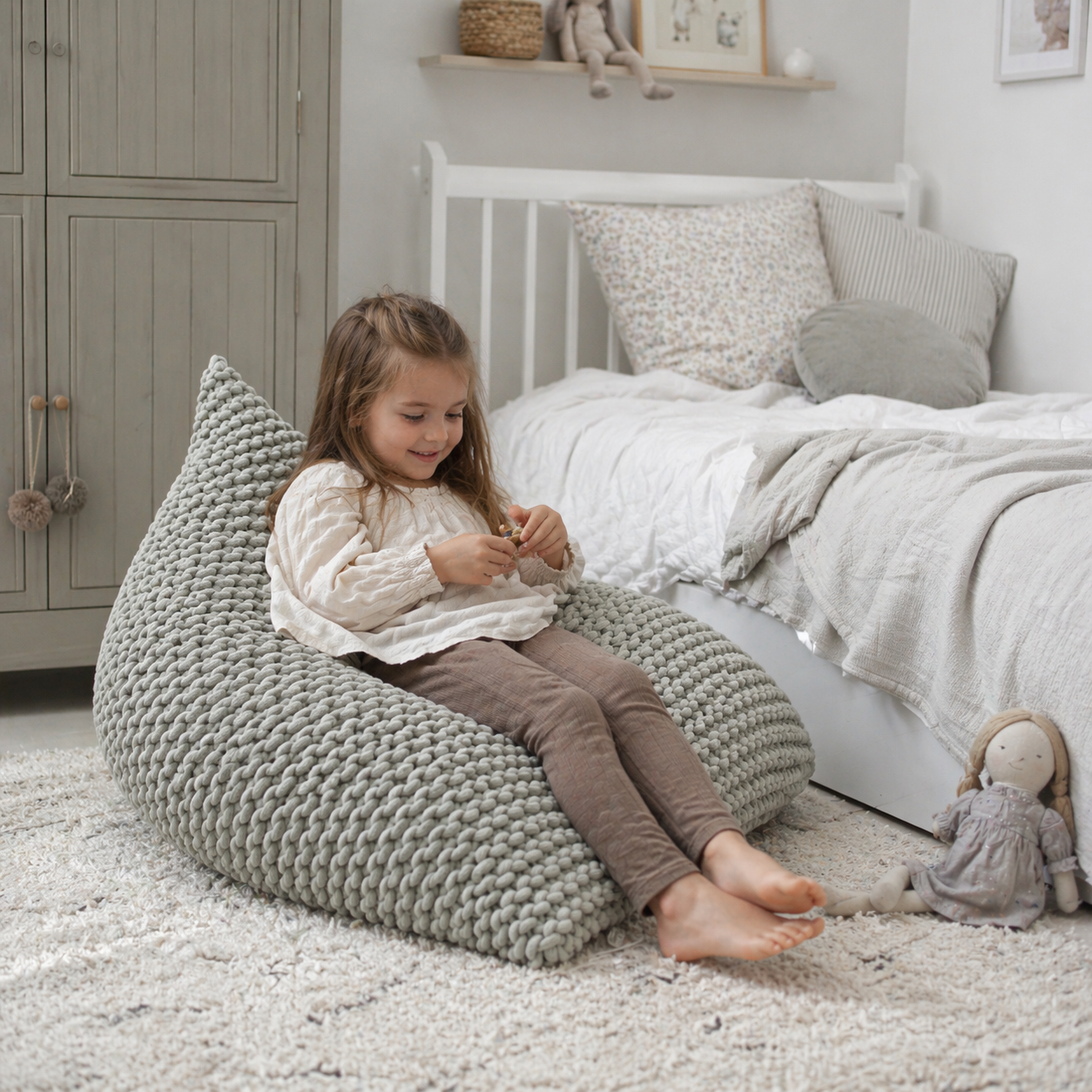 girls bedroom in scandinavian design and a little girl sitting on the chunky knitted bean bag, natural tones bedroom