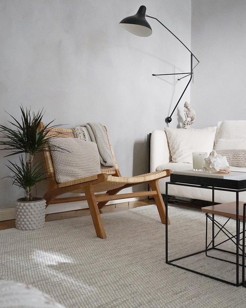 Modern living room with wooden chair, white sofa, and floor lamp.