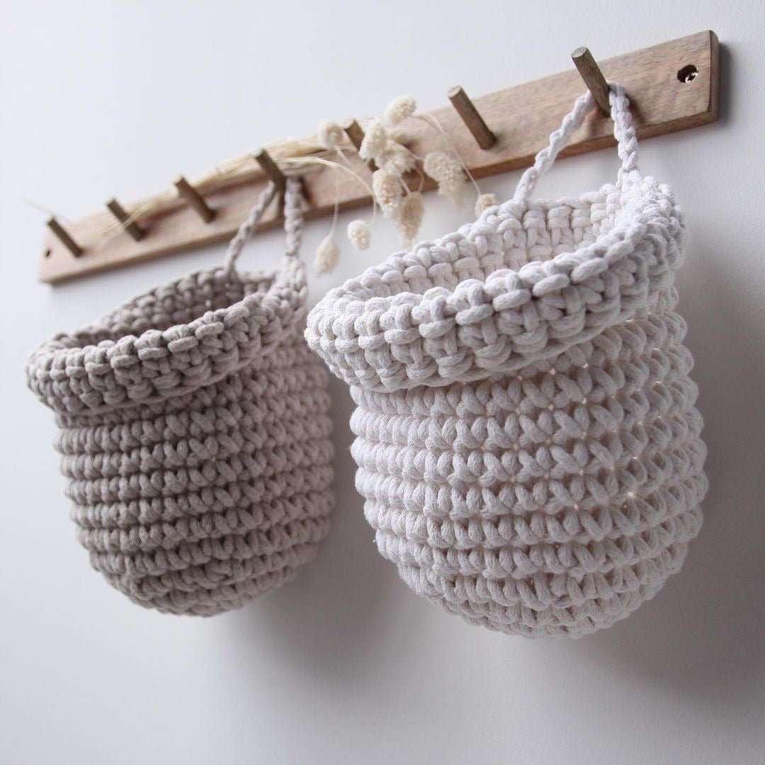 Crochet hanging bags in white and beige colour on the wooden peg hanger