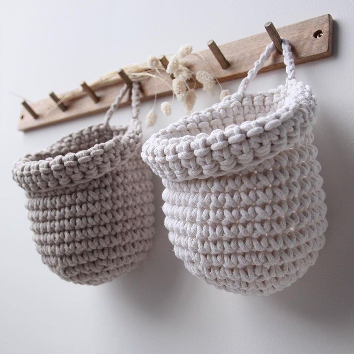 Crochet hanging bags in white and beige colour on the wooden peg hanger
