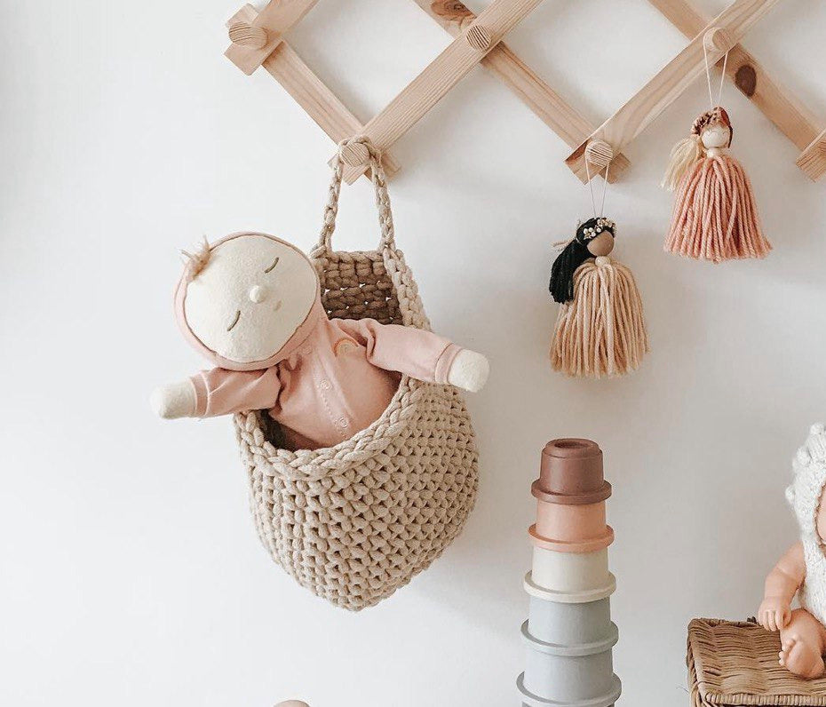 Children's room decor with toys, a woven basket, and tassels on a wooden shelf.