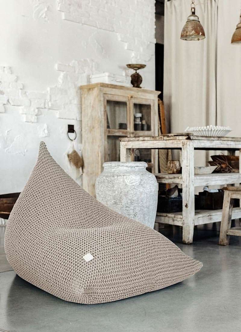 Hand-knitted bean bag in beige cotton yarn shown in a neutral setting