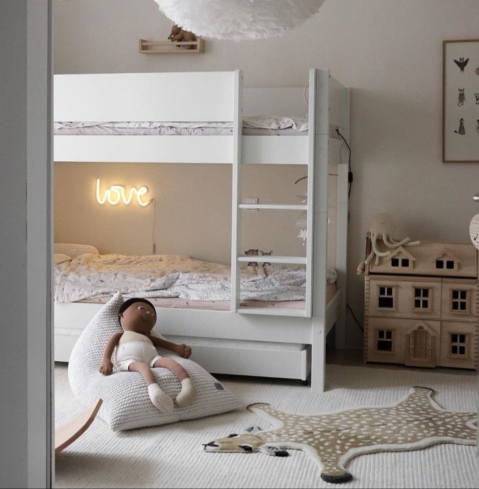 Children's bedroom with white bunk bed, toys, and decorative elements.