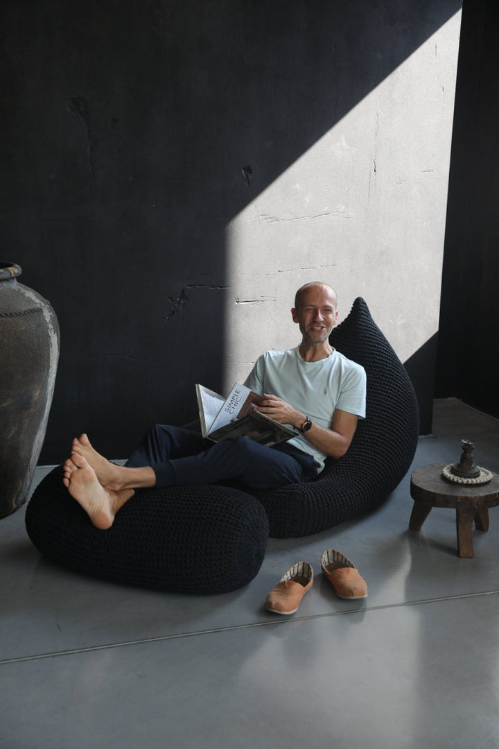 man sitting on a black knitted bean bag