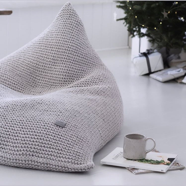 Tactile knitted surface of an oatmeal bean bag in a minimal, empty setting