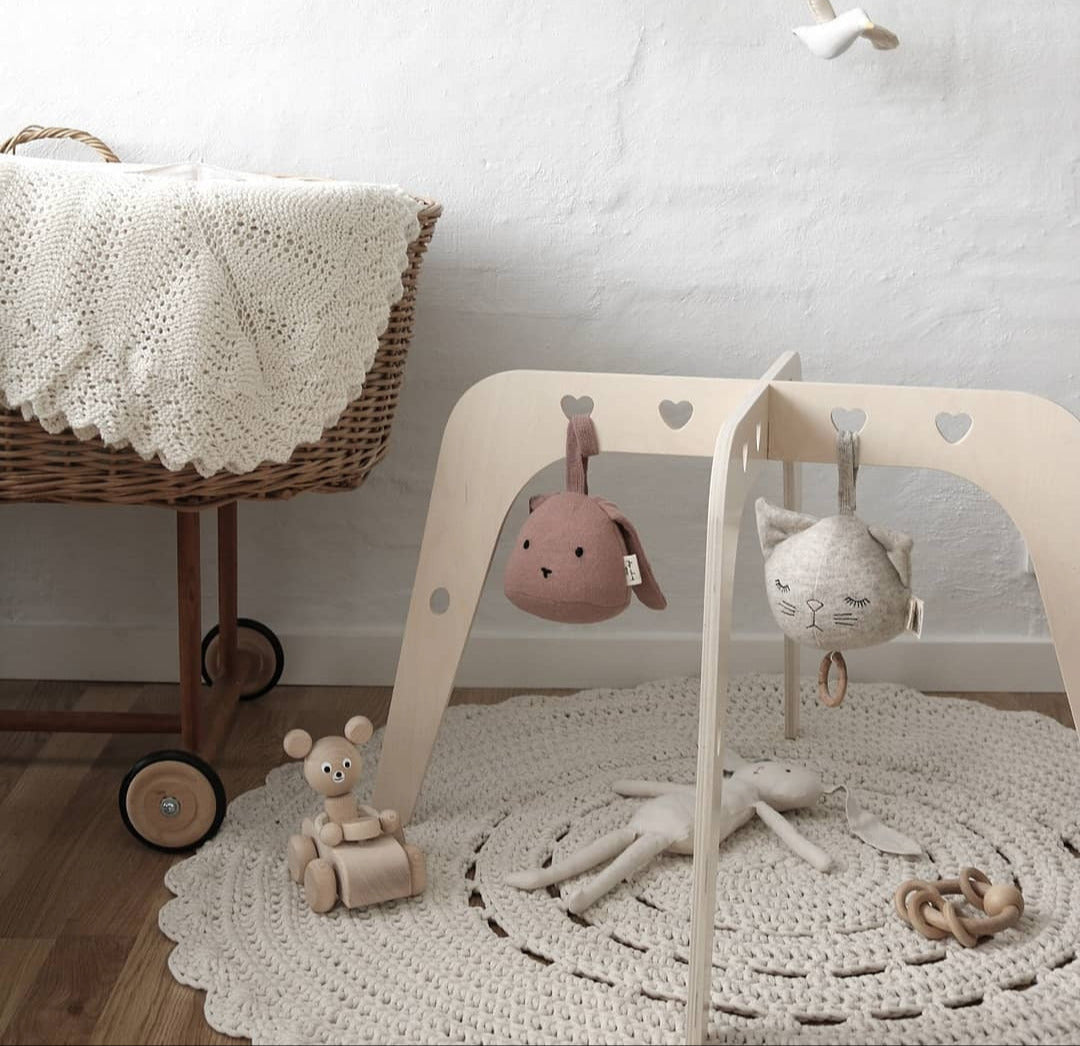 Nursery with wooden baby gym, toys, and wicker crib.