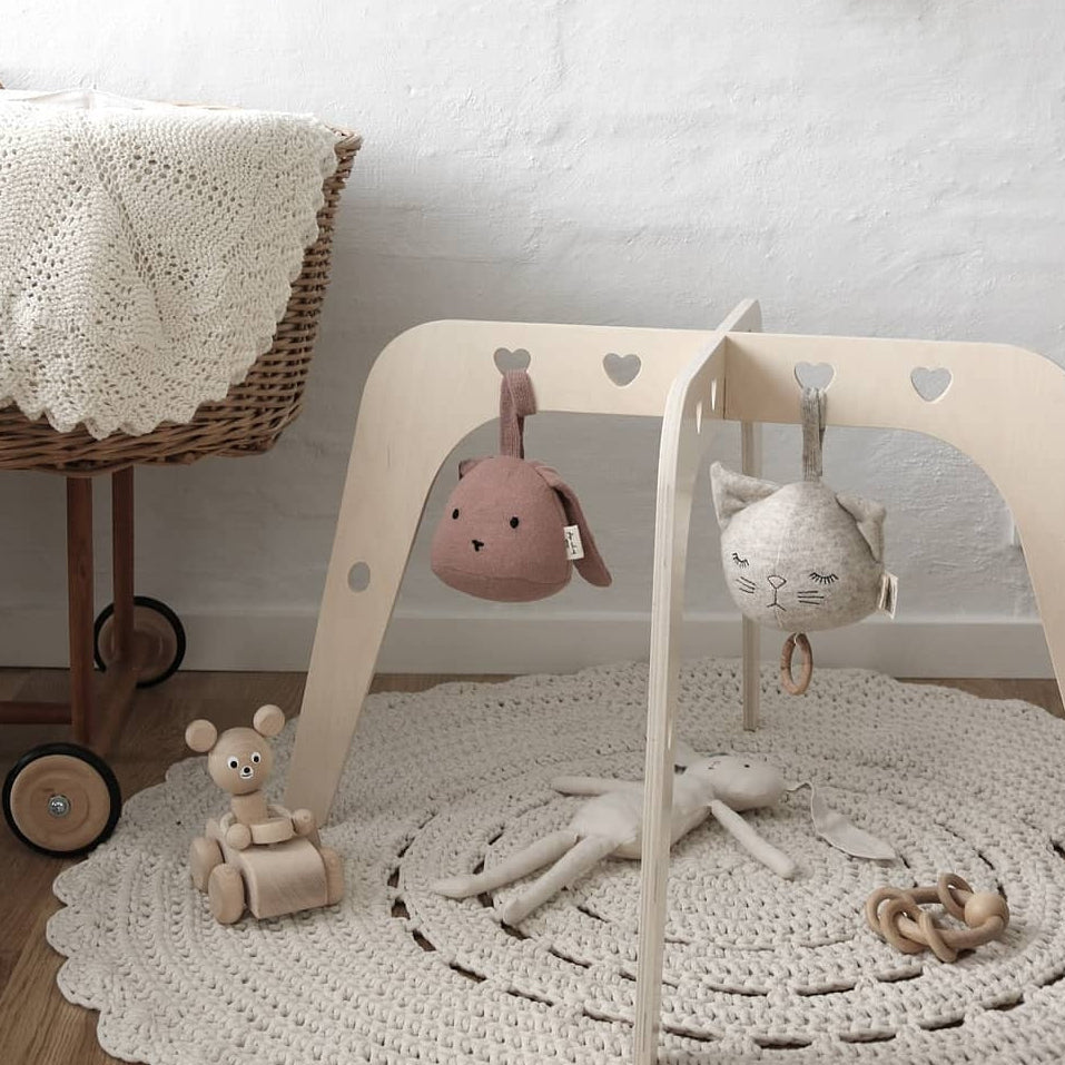 Children's play area with a wooden activity center, toys, and a crib in a room.