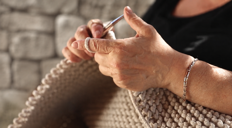 Close-up of hands knitting with a textured background