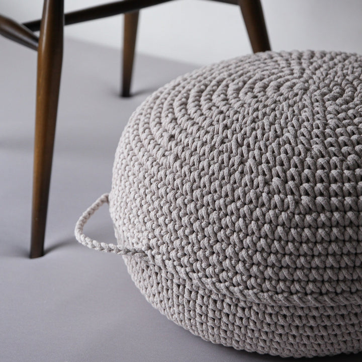 crocheted ottoman by a wooden chair, minimalist footstool with handles