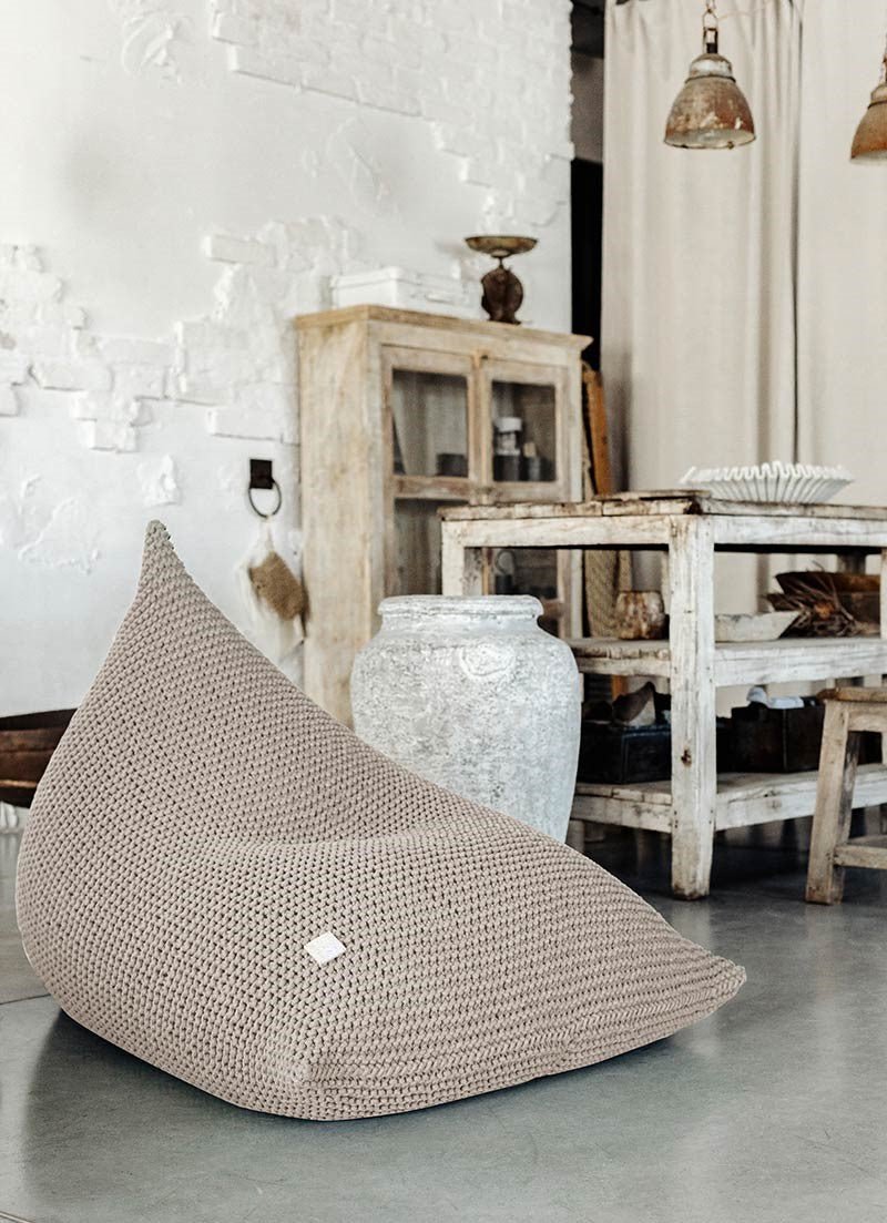 Hand-knitted bean bag in beige cotton yarn shown in a neutral setting
