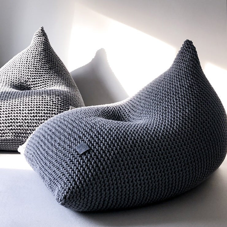 Sculptural dark grey bean bag with visible stitch pattern and curved shape
