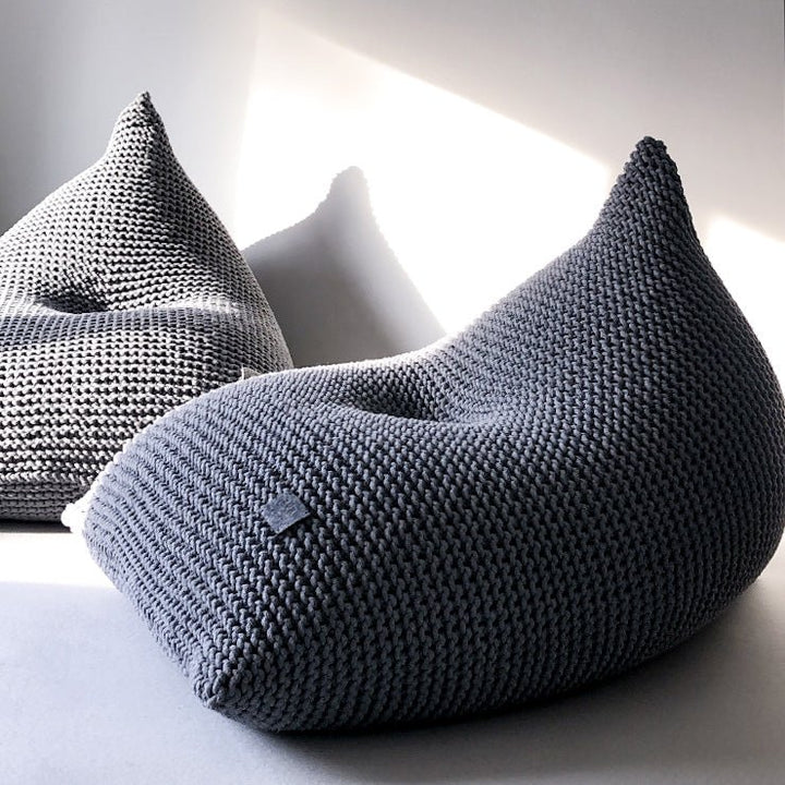 Sculptural dark grey bean bag with visible stitch pattern and curved shape