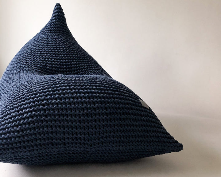 Close-up of a denim blue chunky knit bean bag with soft cotton texture