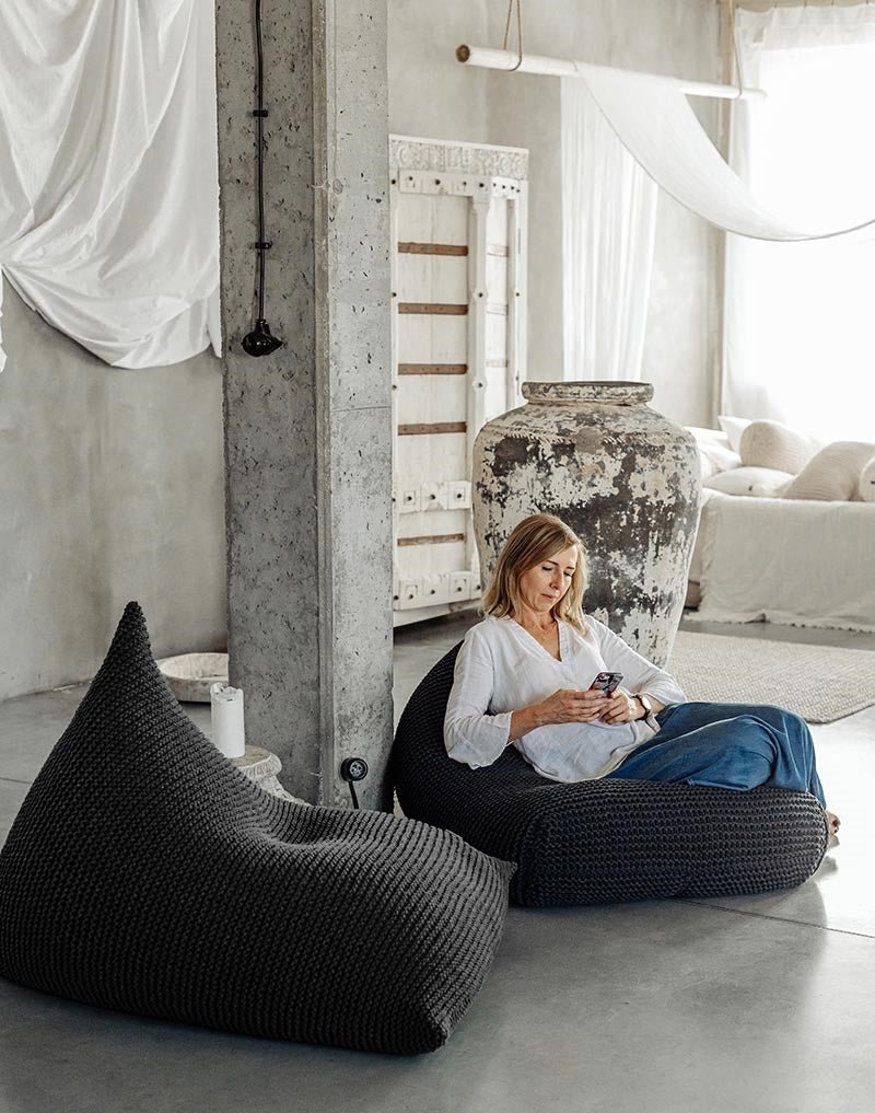 Hand-knitted bean bag in graphite yarn shown in a neutral, minimal setting