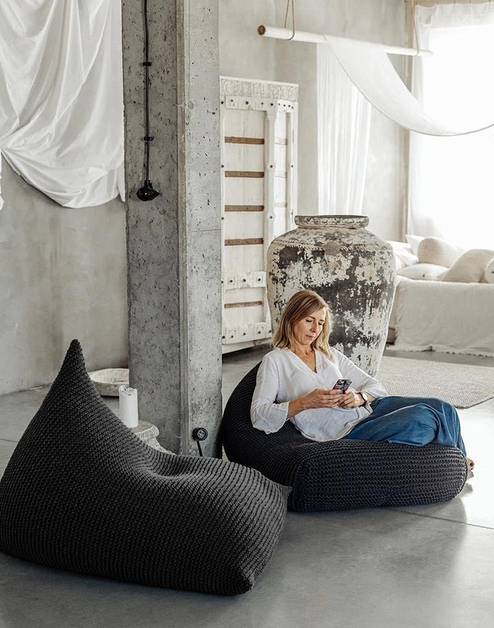 Hand-knitted bean bag in graphite yarn shown in a neutral, minimal setting