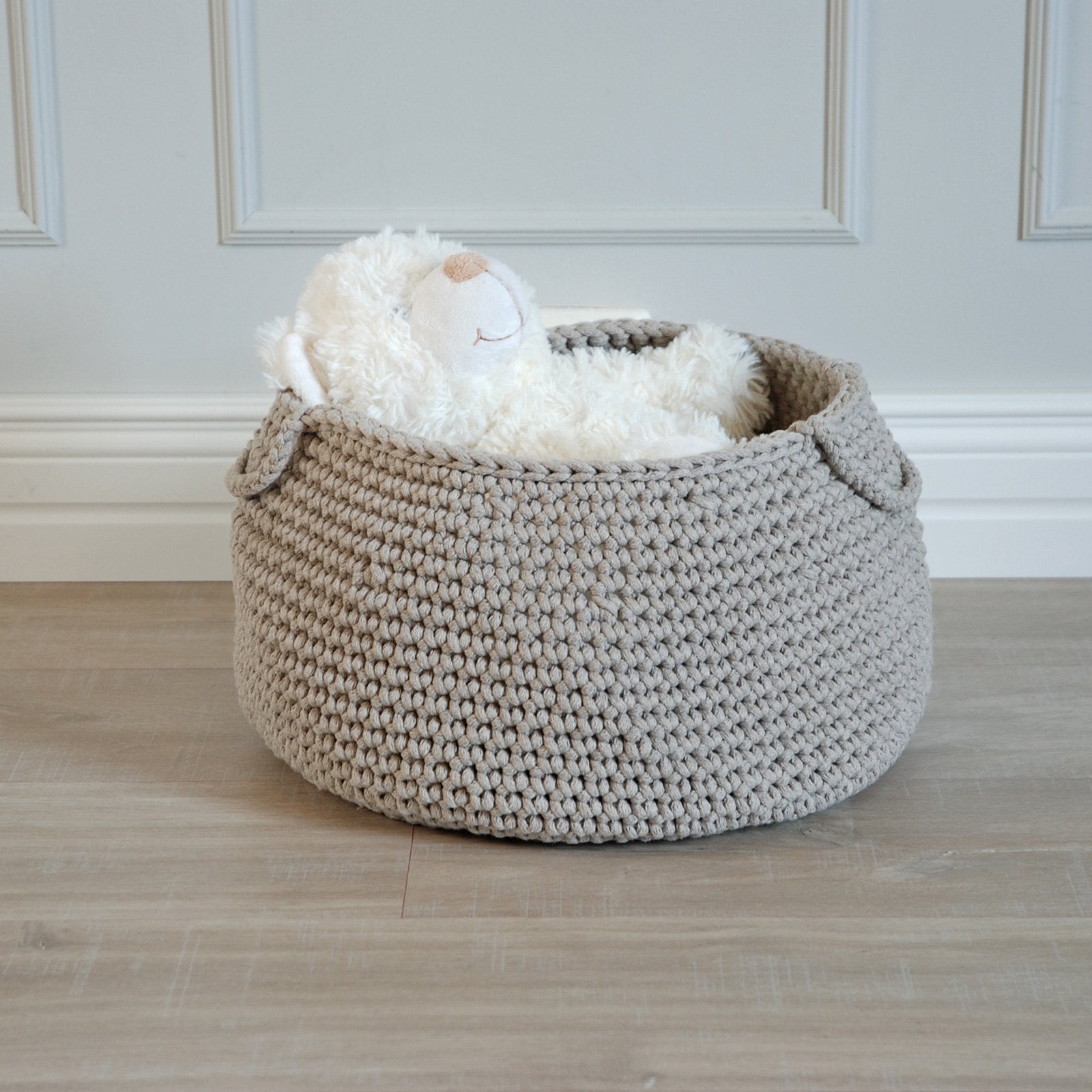Beige crochet toy storage basket holding plush animals, blocks and books
