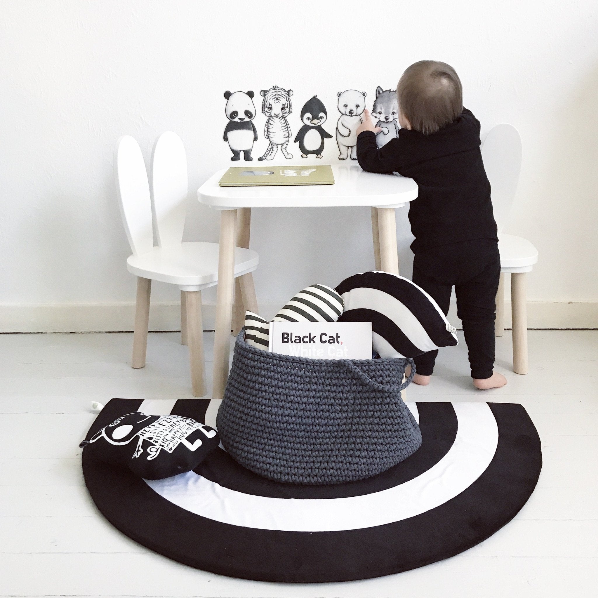 Stylish dark grey crochet basket on a rug, filled with baby toys and plush animals