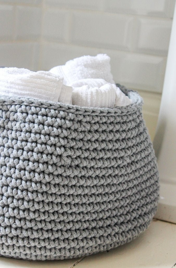 Dark grey crochet basket in bathroom filled with rolled towels, perfect for stylish storage