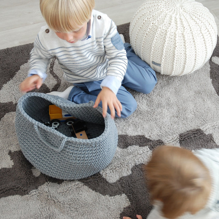 Dark grey crochet basket filled with soft toys and blocks in a stylish nursery