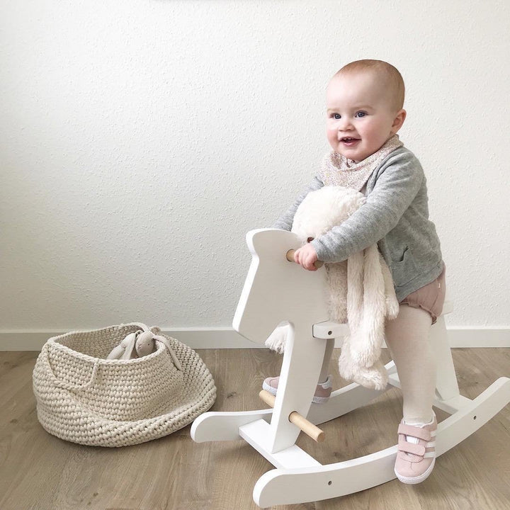 Neutral crochet basket in ivory holding plush animals and blocks in a playroom