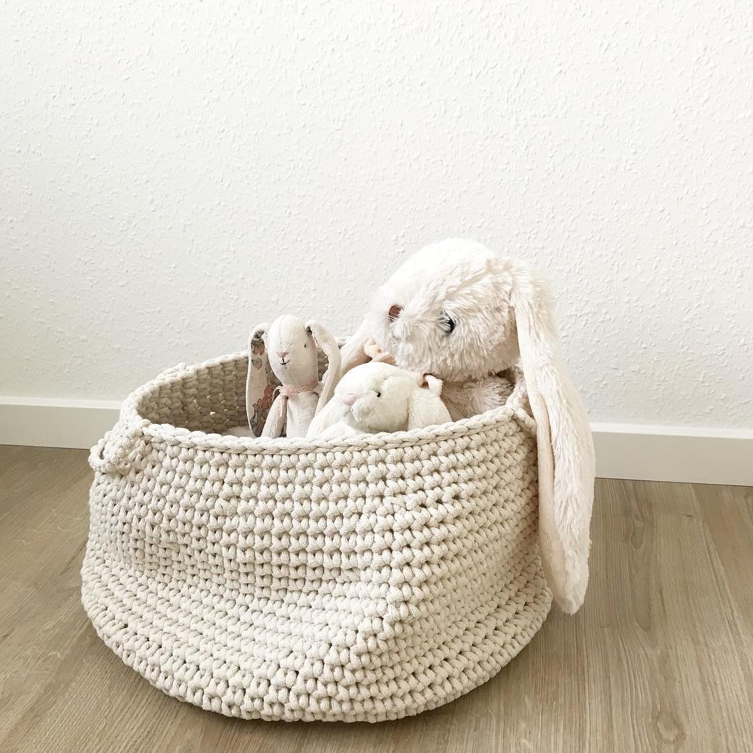 Light cotton crochet basket with handles, filled with toys in a calm, minimalist kids’ room