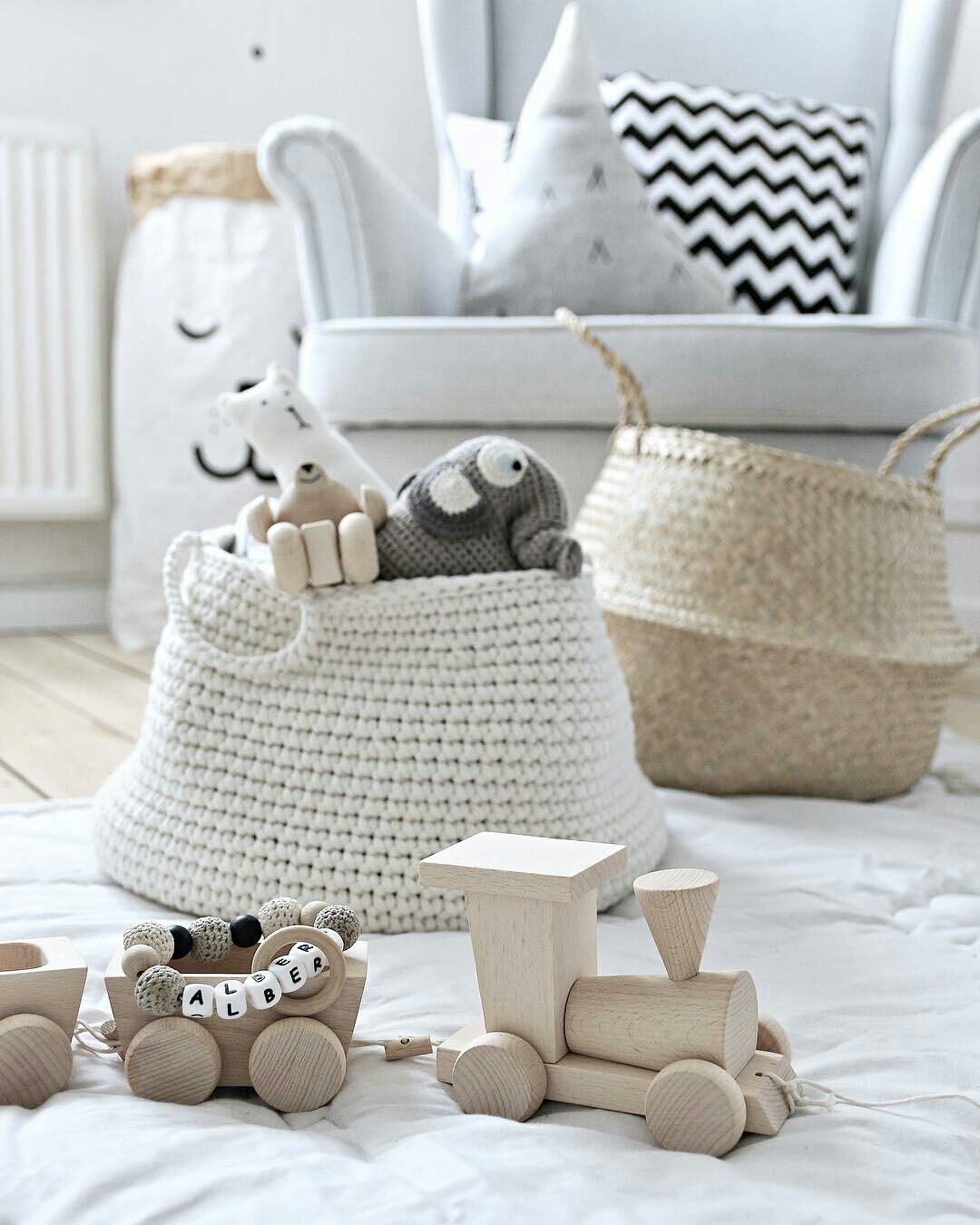 Ivory crochet basket filled with soft toys and baby items in a light-toned nursery