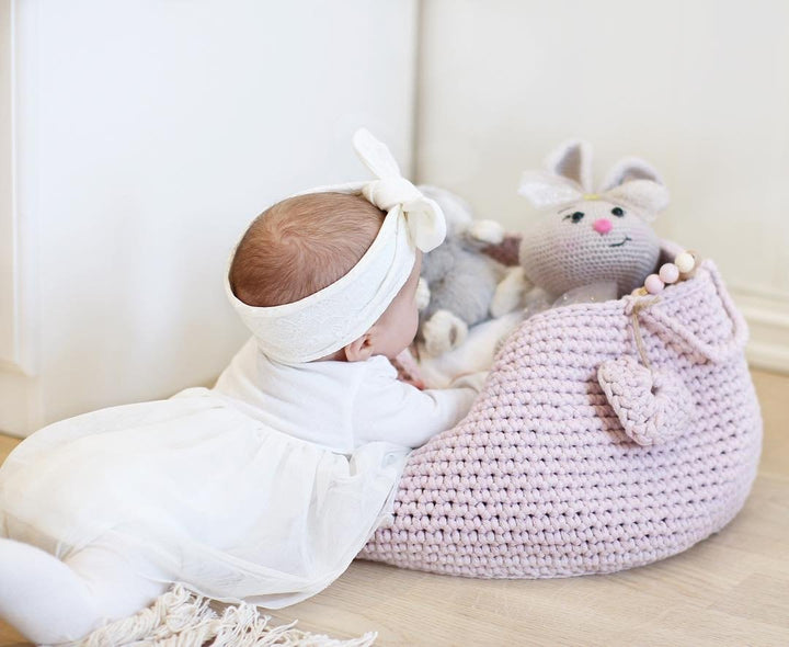 Soft pink cotton basket with handles, neatly storing toys in a pastel-themed nursery